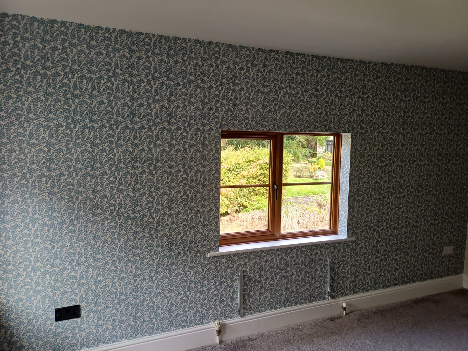 Finished floral wallpaper around a timber window in a sitting room